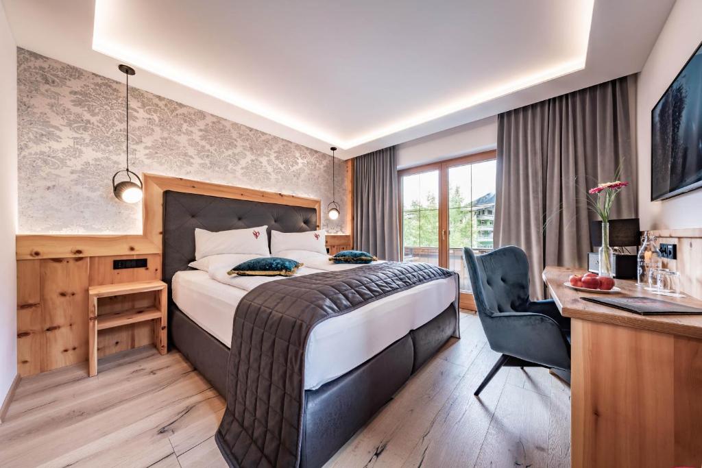 a hotel room with a large bed and a desk at Hotel Gasthof Perauer in Mayrhofen