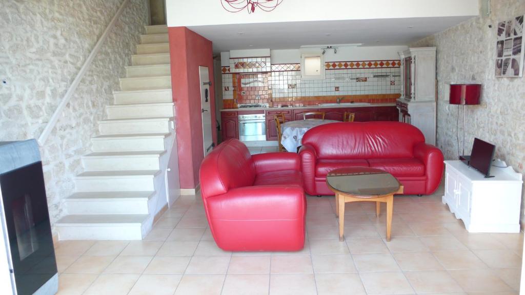 un soggiorno con divano rosso e una scala di Le Gîte ROUGE a Saujon