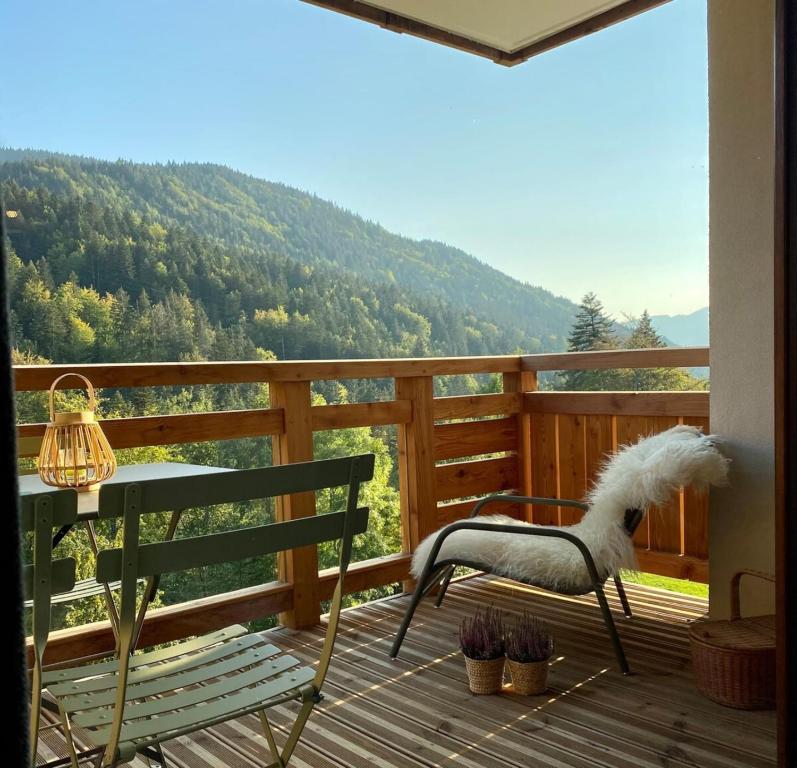 a chair and a table on a deck with a view at Les Lucioles - Charming flat in the mountains in Saint-Jean-de-Sixt