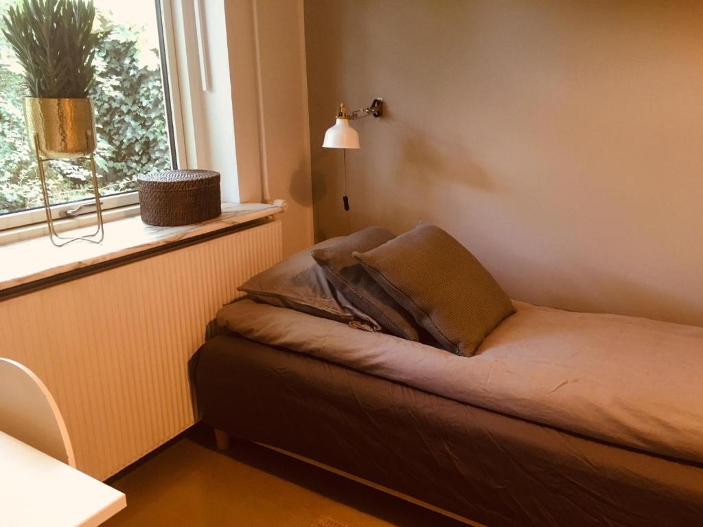 a bed in a room with a window and a pillow at Villa med private værelser og delt køkken/badrum, centralt Viby sj in Viby