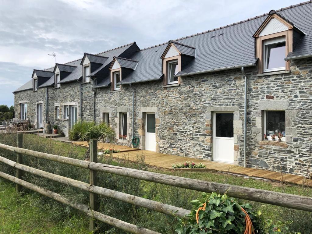 une maison en pierre avec une clôture devant elle dans l'établissement Le Bout du Monde, à Bricqueville-sur-Mer