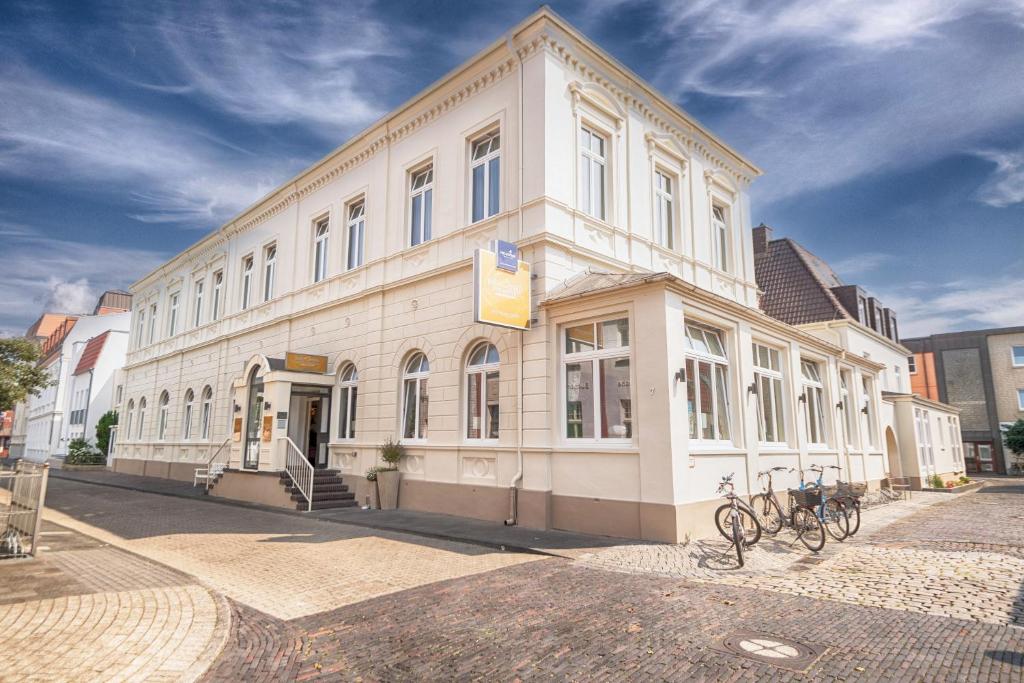 un edificio blanco con bicicletas estacionadas frente a él en Inselhotel Bruns, en Norderney