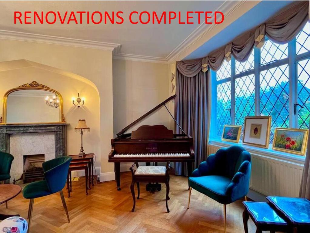 a living room with a grand piano and chairs at Suburban London Villa with Garden in Kingston upon Thames