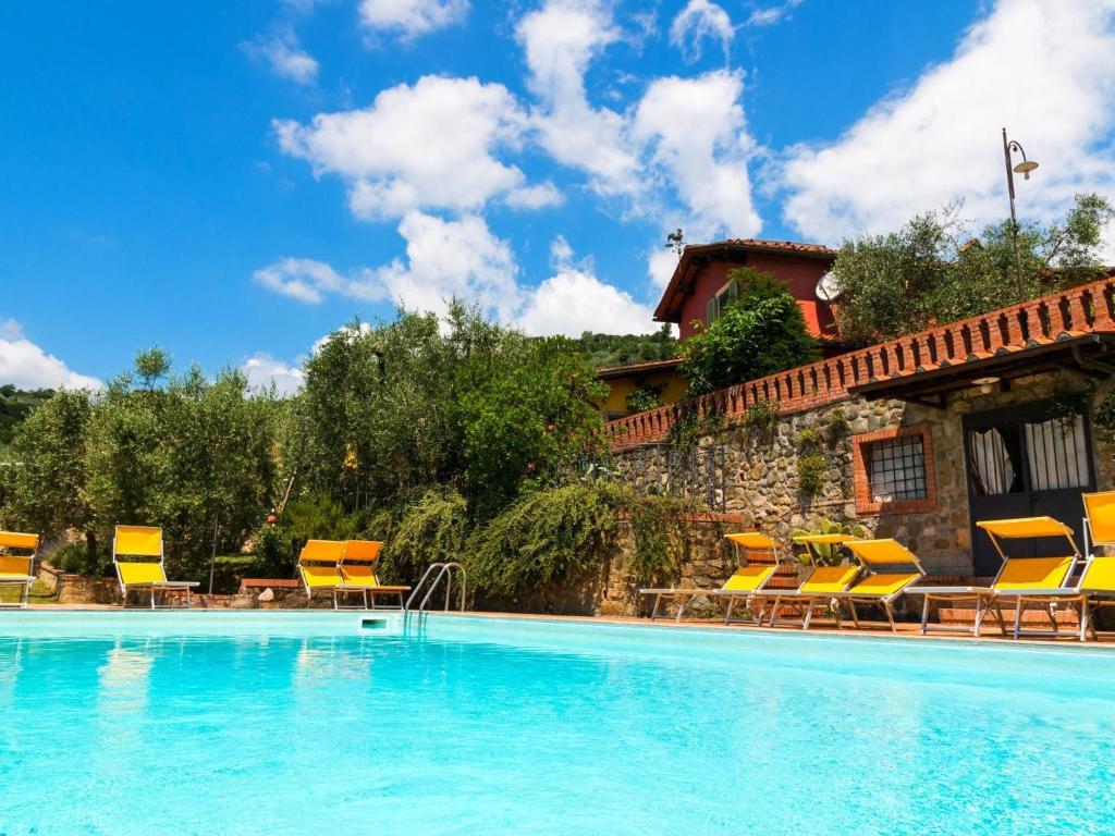 a swimming pool with chairs and a house at Bright Farmhouse in Montecatini Terme with Swimming Pool in Pieve a Nievole