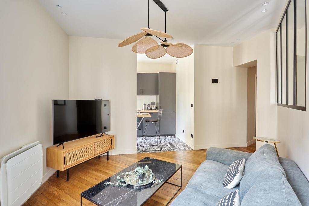 un salon avec un canapé bleu et une télévision à écran plat dans l'établissement Apartment Invalide by Studio prestige, à Paris