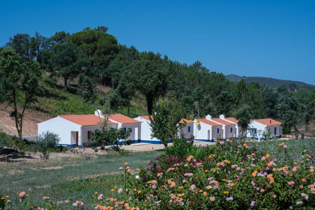 eine Reihe von Häusern auf einem Hügel mit einem Blumenfeld in der Unterkunft Vale da Cassiopeia in Cercal