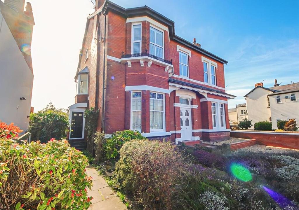 a large red brick house with a garden in front of it at Spacious Victorian Birkdale Apartment with Garden in Southport