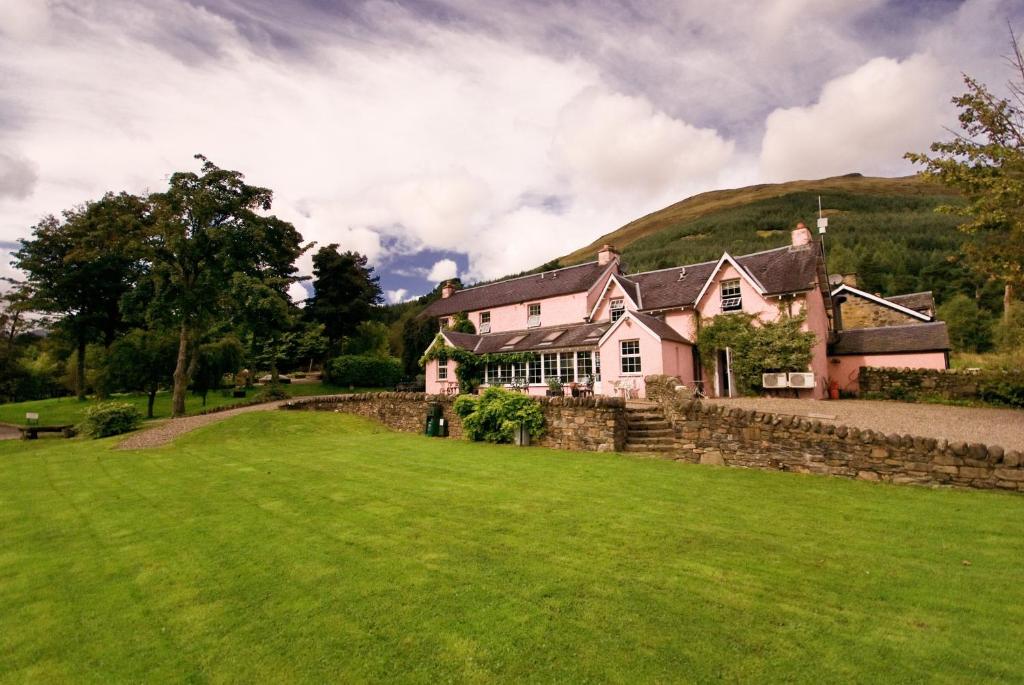 una casa en una colina con césped verde en Monachyle Mhor Hotel, en Lochearnhead