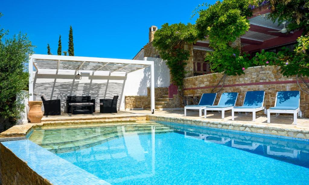a swimming pool with blue chairs and a grill at Maria Elena Villas I in Lagomandra