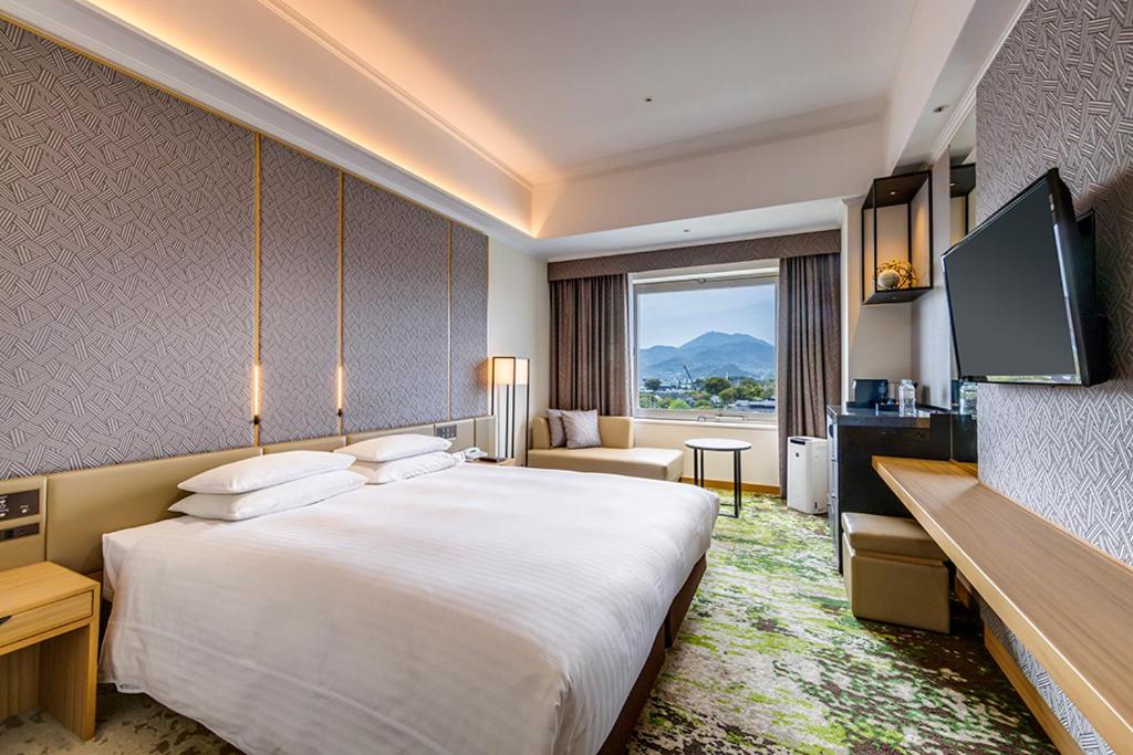 a hotel room with a large bed and a television at Hotel Nikko Kumamoto in Kumamoto