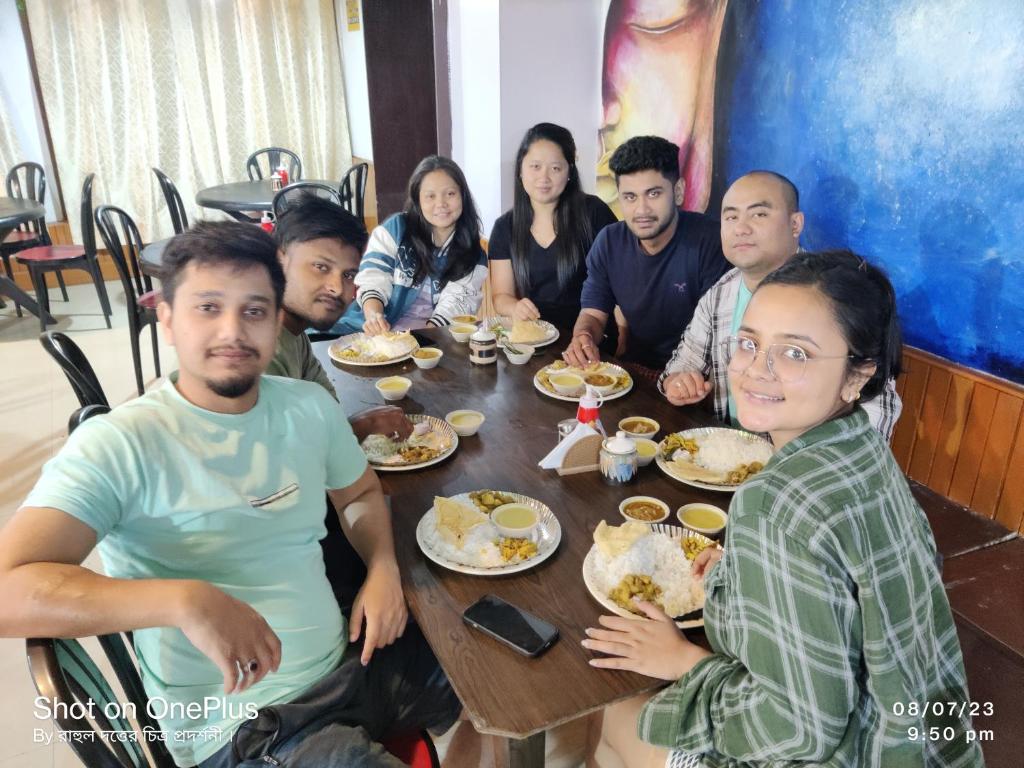 un grupo de personas sentadas alrededor de una mesa comiendo comida en Bubble Beds, en Darjeeling