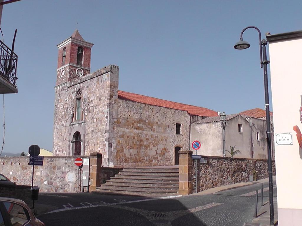 een oud stenen gebouw met een klokkentoren en een trap bij Sardinia Experience in Villamassargia