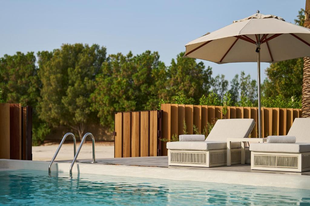a swimming pool with two chairs and an umbrella at ERTH Abu Dhabi Hotel in Abu Dhabi