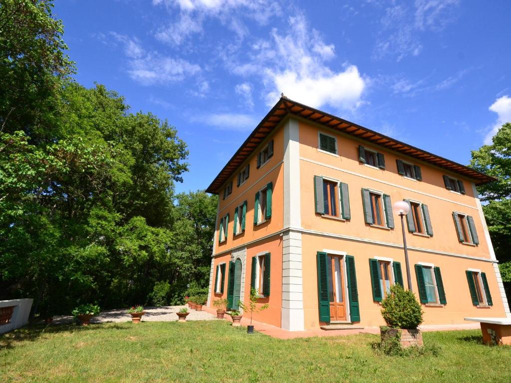 uma casa grande com persianas verdes num campo em Lovely holiday home in Montefiridolfi with hill view em Montefiridolfi
