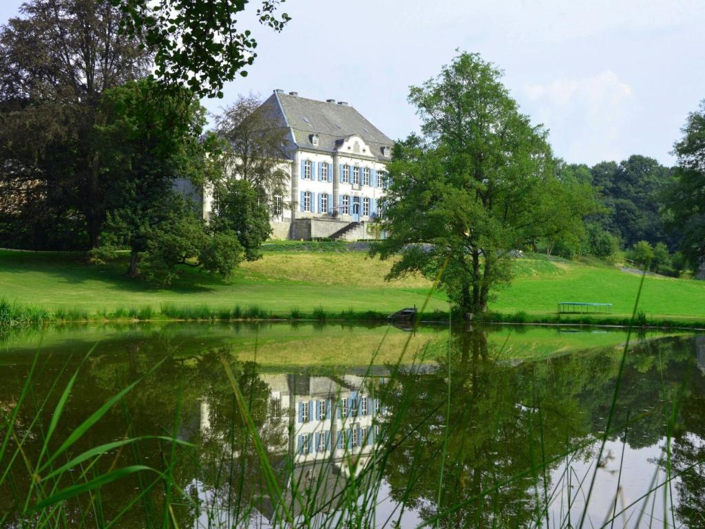 a large house with a reflection in a pond at Luxurious castle in Marchin with infrared sauna in Tharoul