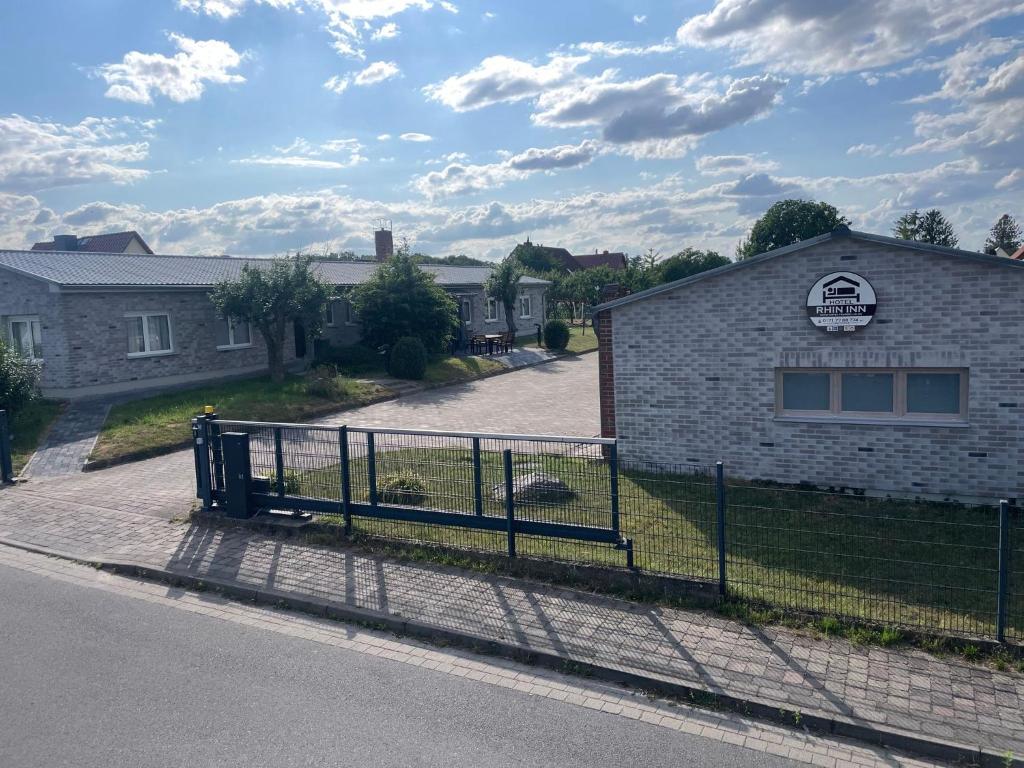 une clôture devant un bâtiment muni d'un panneau dans l'établissement Hotel Rhin Inn, à Fehrbellin