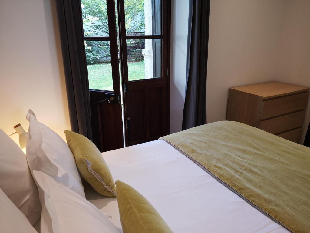 a bedroom with a bed with white sheets and a window at Villa Saint Enogat in Aix-les-Bains