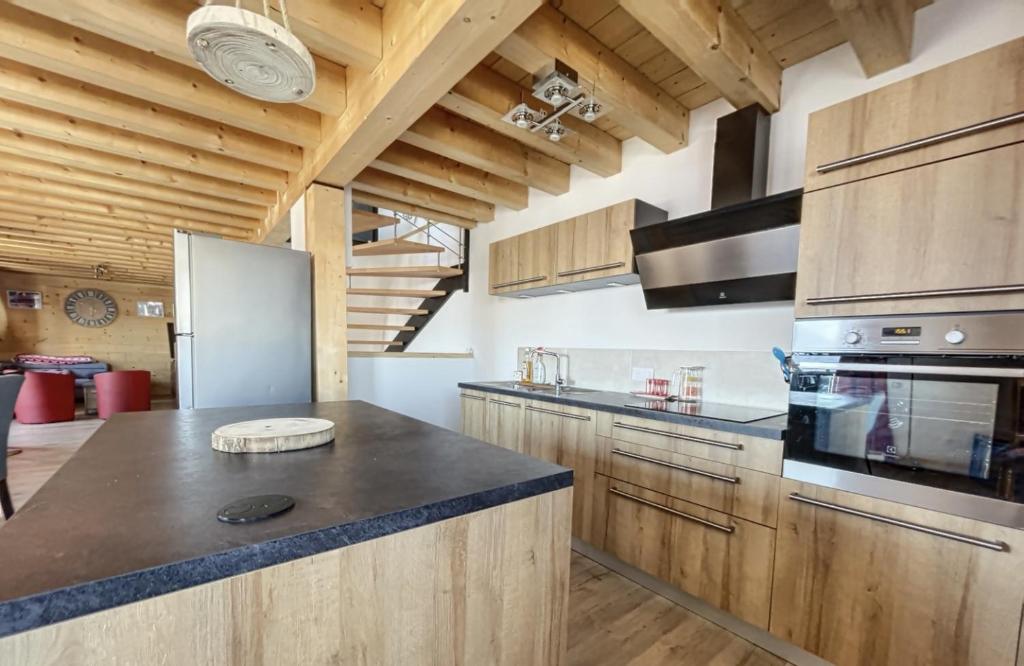 a large kitchen with wooden cabinets and a refrigerator at Chalet la Cochette in La Toussuire