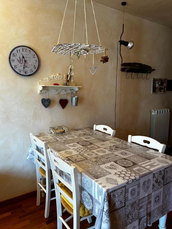mesa de comedor con sillas y reloj en la pared en Chalet Montana - Borgo Le stalle Lunghe, en Prato Nevoso