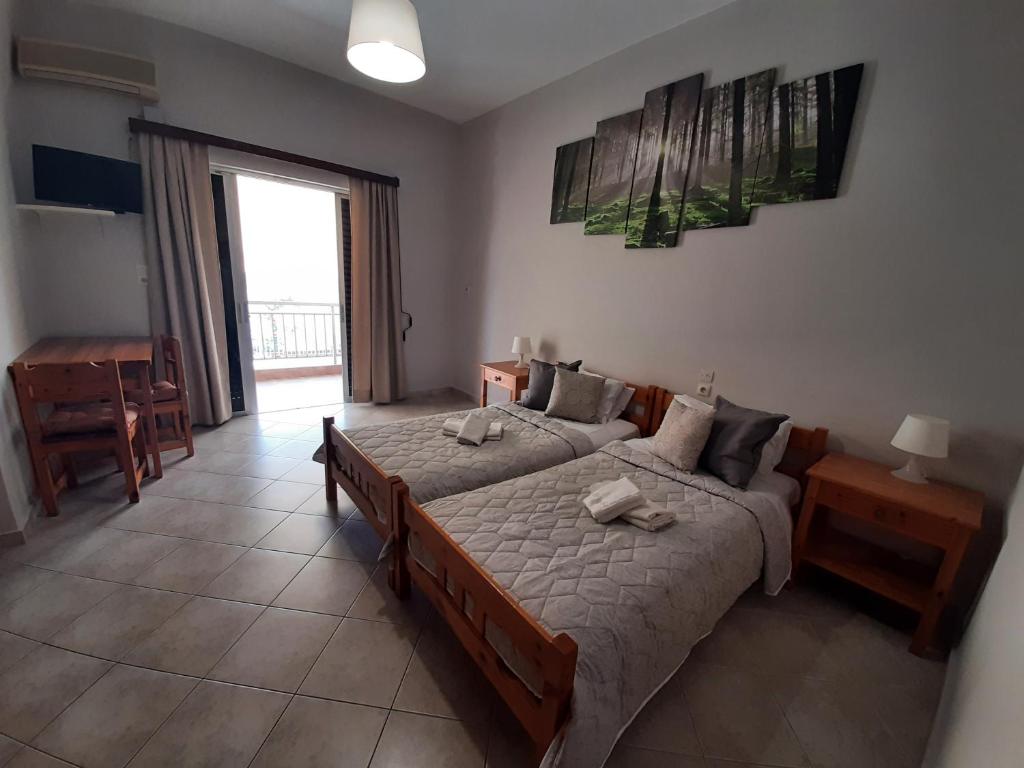 a bedroom with two beds and a table and a window at Zagas Hotel Ξενοδοχειο Ζάγκας in Rovies