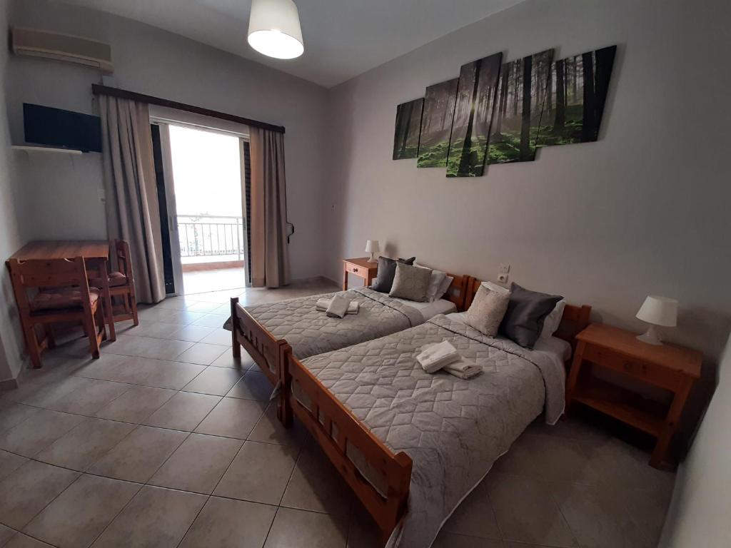 a bedroom with two beds and a table and a window at Zagas Hotel &Xi;&epsilon;&nu;&omicron;&delta;&omicron;&chi;&epsilon;&iota;&omicron; &Zeta;ά&gamma;&kappa;&alpha;&sigmaf; in Rovies