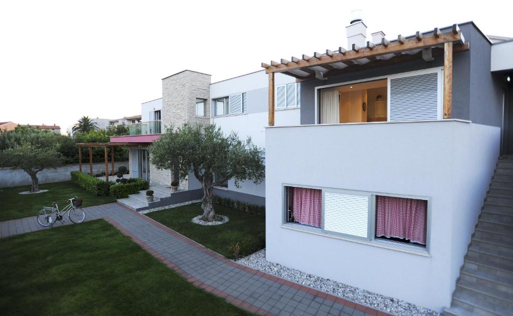 una casa blanca con un pequeño jardín frente a ella en Apartments Villa Clementa, en Zadar