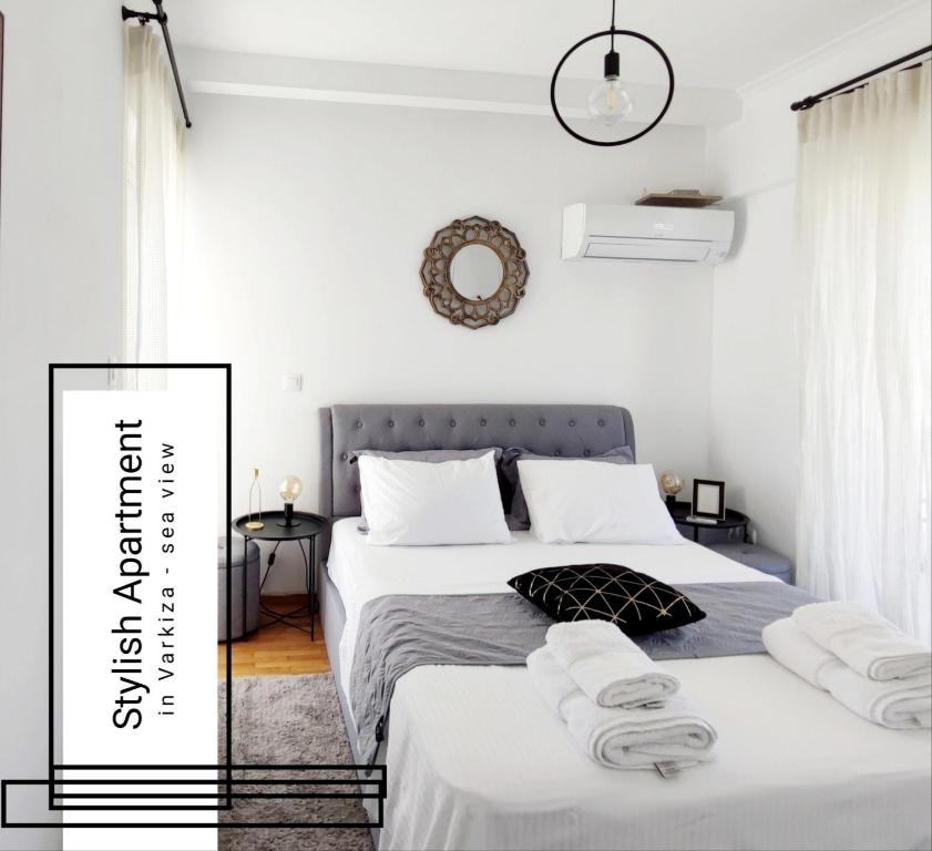 a white bedroom with two beds and a mirror at Varkiza Sea View Apartment - Free Parking in Vari