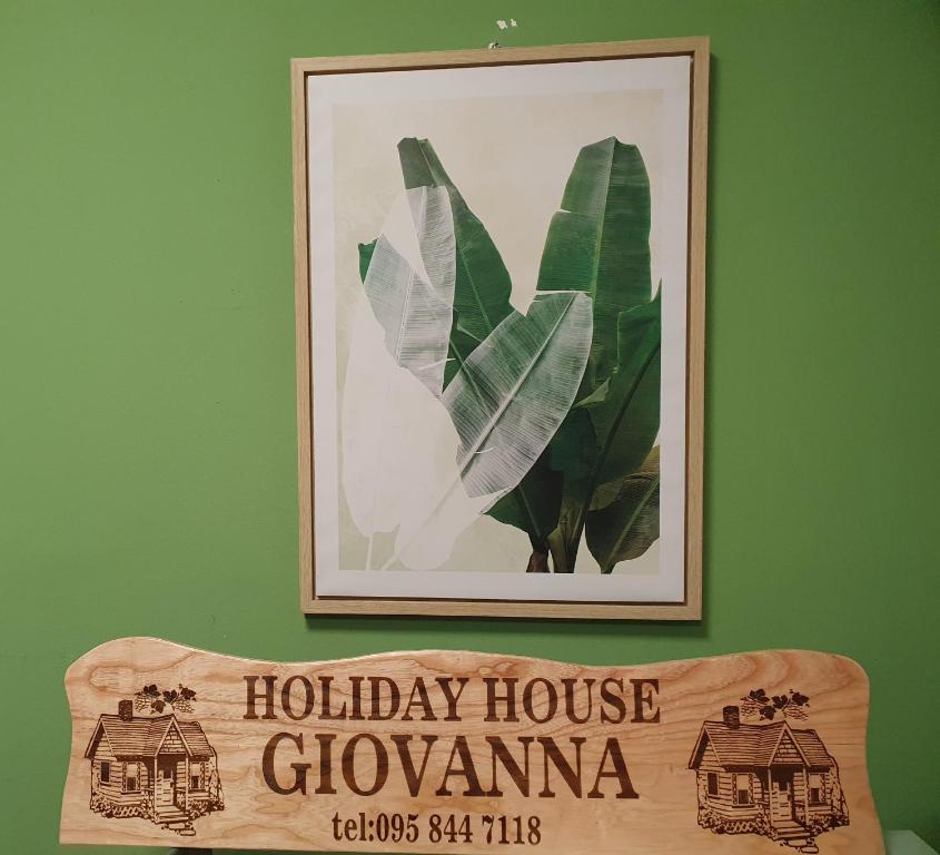 a picture hanging on a green wall with a wooden sign at Holiday house Giovanna in Vojnić