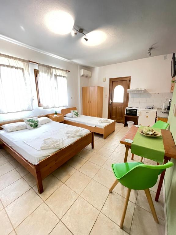 a large room with two beds and a green chair at Cactus rooms in Stratoni