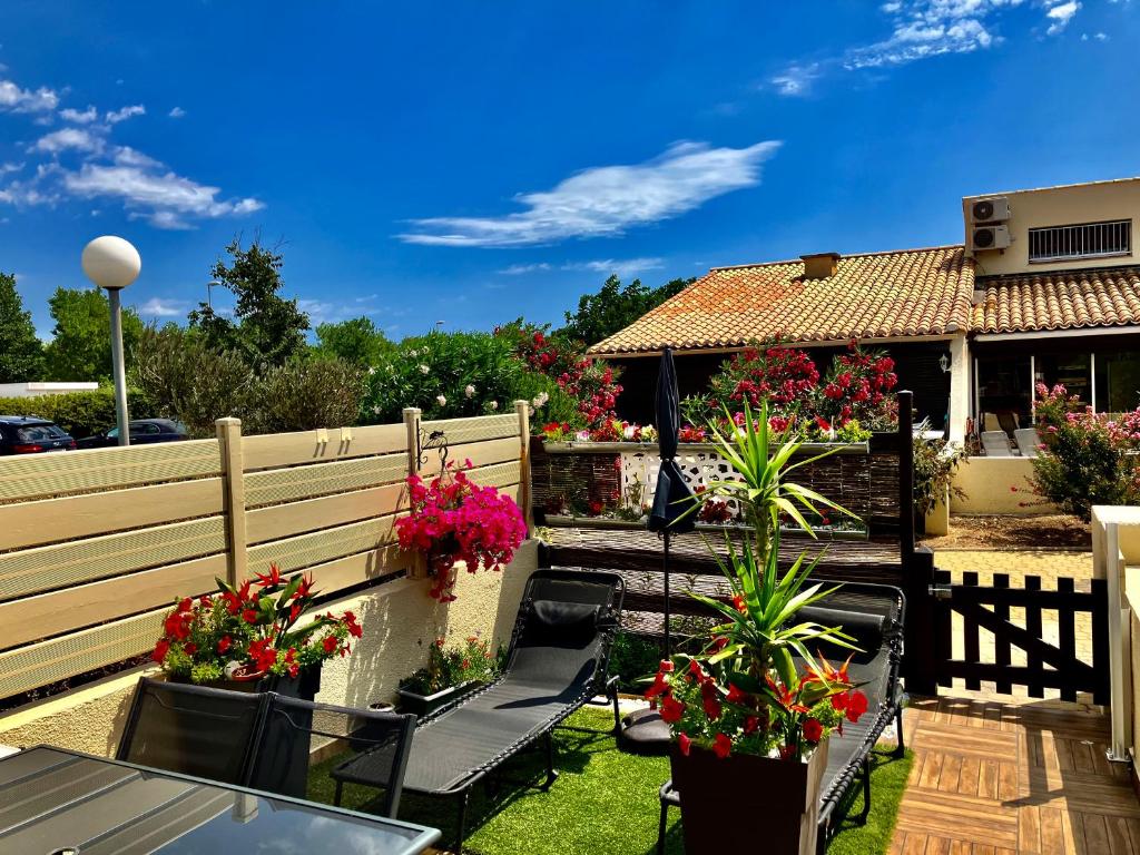 patio z krzesłami i doniczkami oraz dom w obiekcie Naturiste Heliovillage Villa de Standing w Cap d'Agde