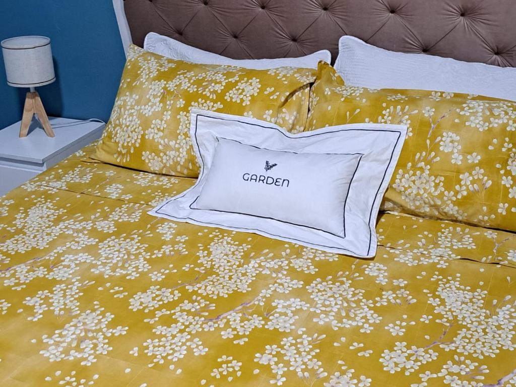 a bed with a yellow comforter with a white pillow at GARDEN in Milan