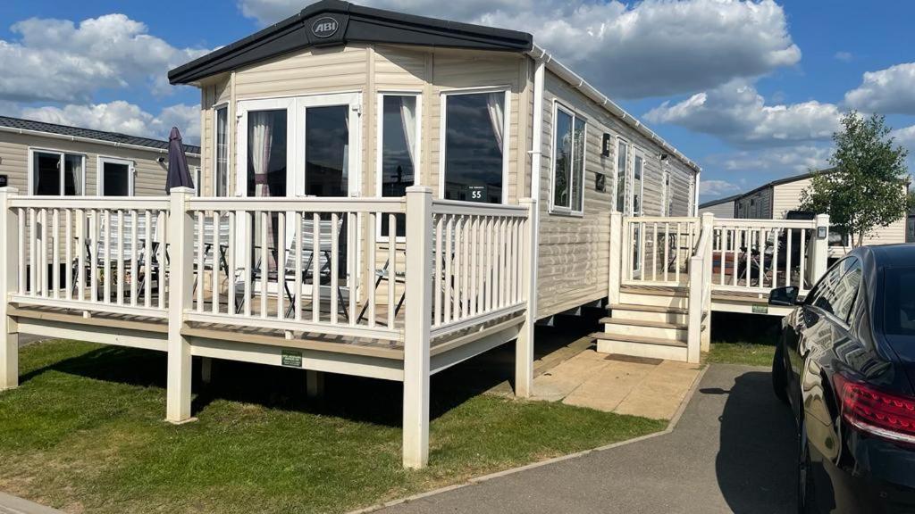 a small white house with a porch and a car at 3 Bedroom Caravan in Tattershall lakes Holiday Park in Tattershall