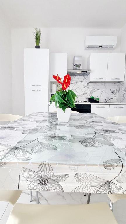a kitchen with a table with a vase with a red flower at Guest Holiday Piave 4 in Reggio Emilia
