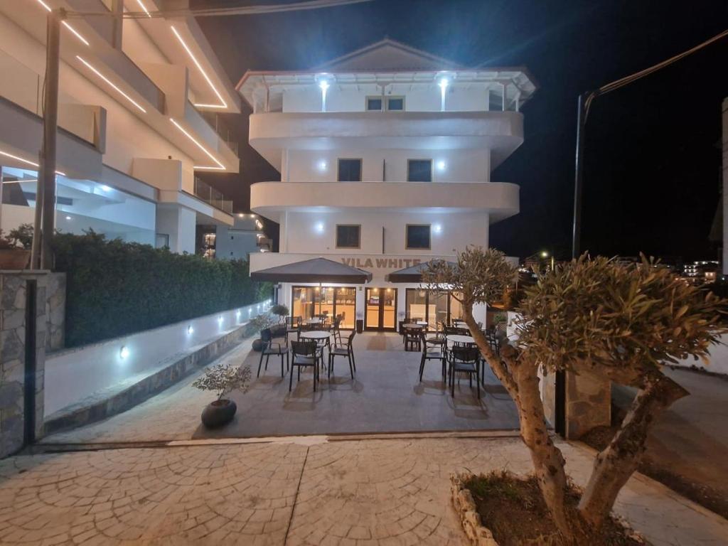 a building with tables and chairs in a courtyard at night at Villa White in Ksamil
