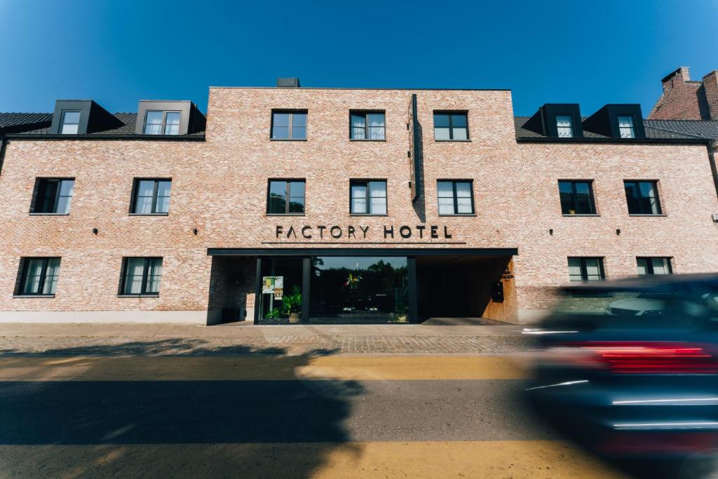 a red brick hotel with a sign on it at Factory Hotel in Beveren