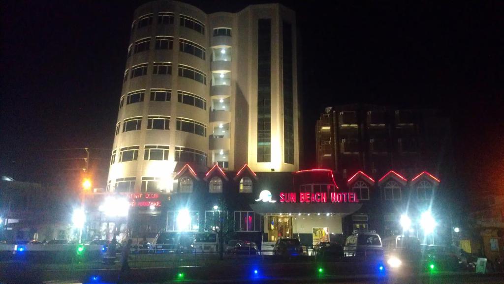 wysoki budynek z oświetleniem przed nim w nocy w obiekcie Sun Beach Hôtel w mieście Kotonu