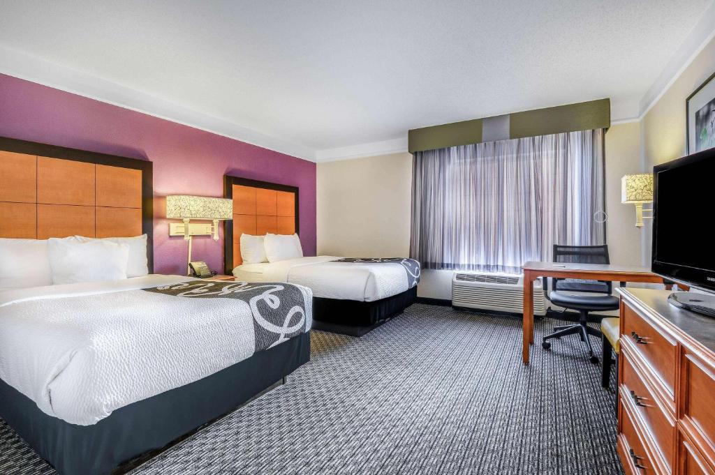a hotel room with two beds and a flat screen tv at La Quinta by Wyndham Myrtle Beach Broadway Area in Myrtle Beach