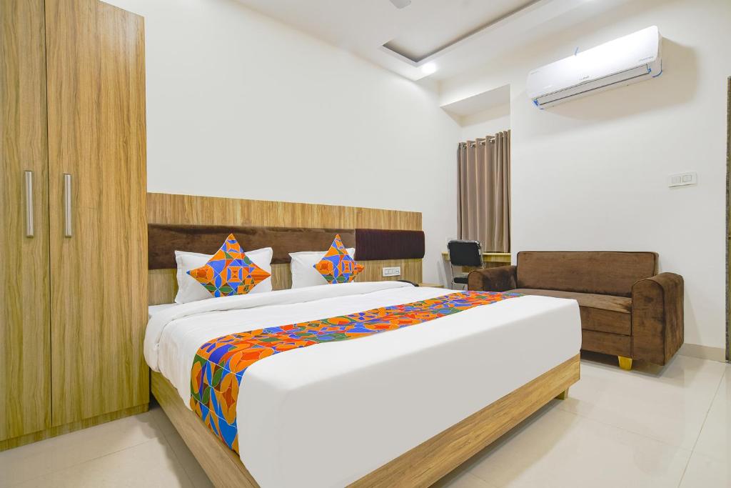 a bedroom with a large bed and a couch at FabHotel Suraj Kunj in Indore