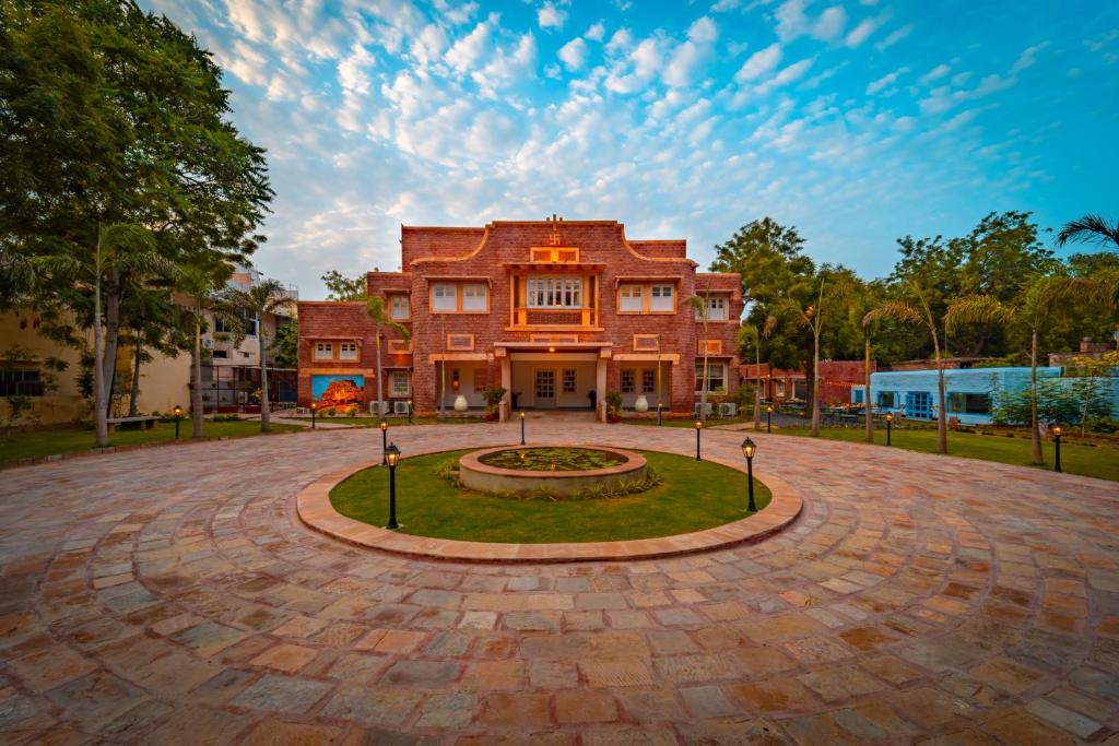 einem großen roten Backsteingebäude mit kreisförmiger Auffahrt in der Unterkunft Tree Of Life Bhadrajun House, Jodhpur in Jodhpur