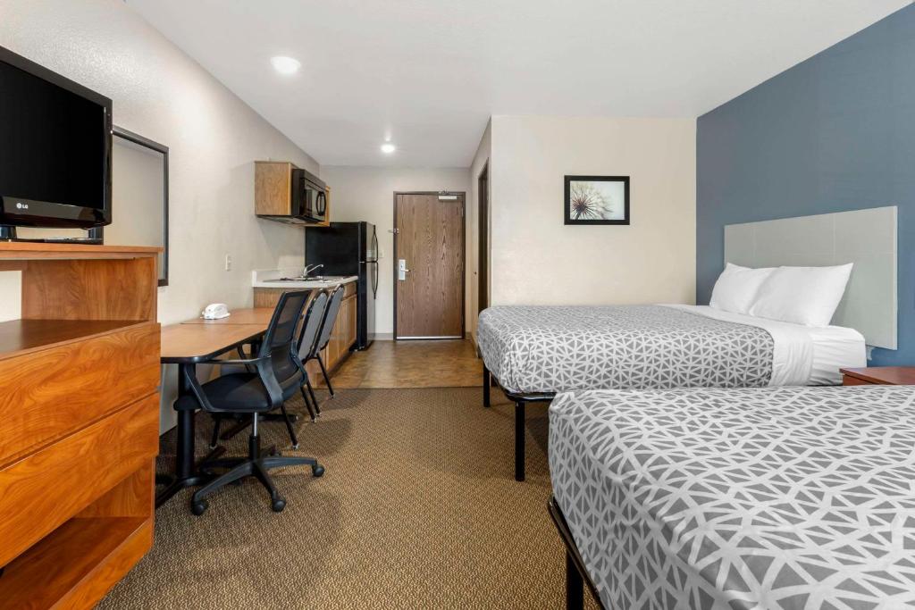 WoodSpring Suites Raleigh Garner في Edmondson: غرفة فندقية بسريرين ومكتب