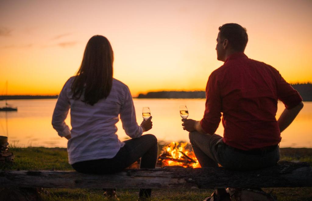a man and a woman sitting around a fire with wine glasses at Ye Olde Argyler Lodge in Pubnico