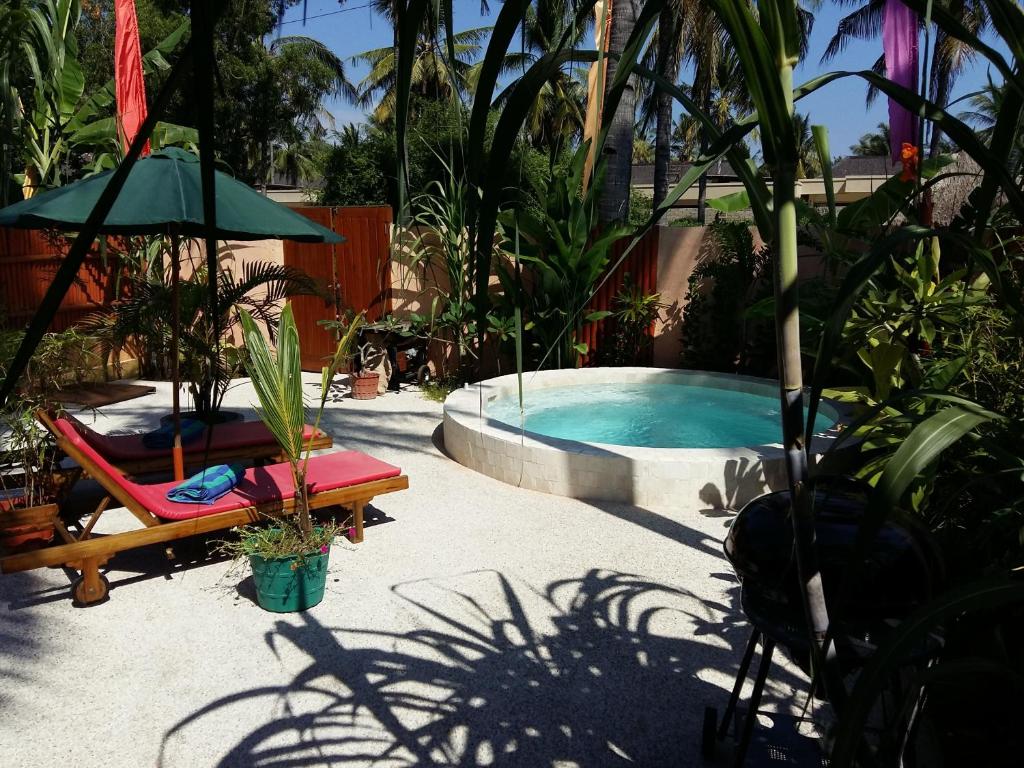 a swimming pool with a chair and a umbrella and a chair sidx sidx at Santan Gili Cottages in Gili Trawangan