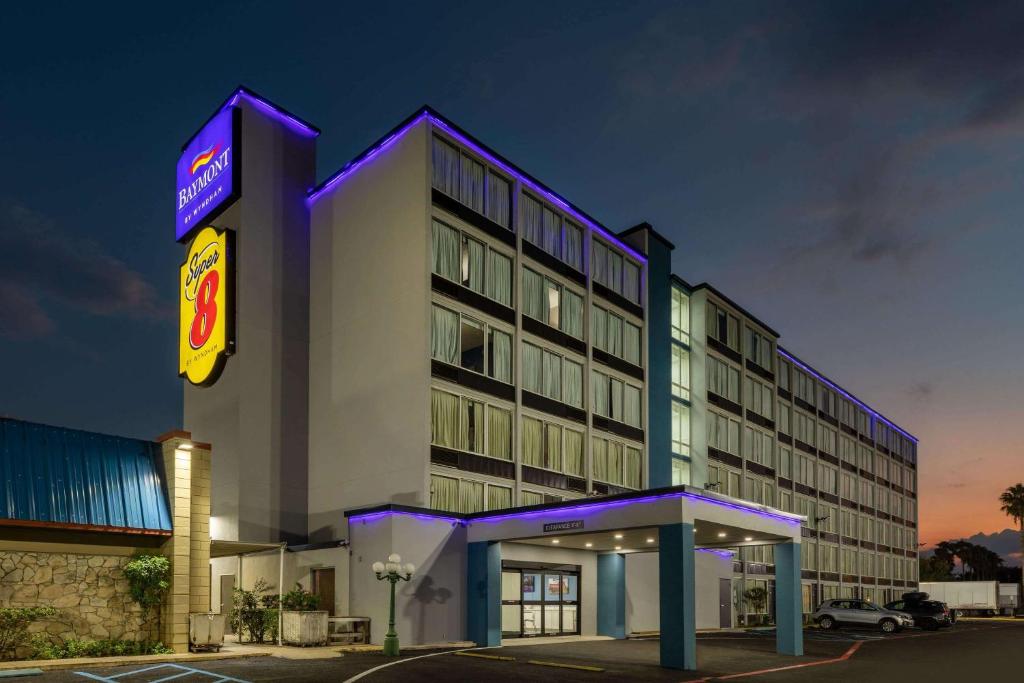 ein Hotelgebäude mit einem Neonschild davor in der Unterkunft Super 8 by Wyndham Laredo in Laredo