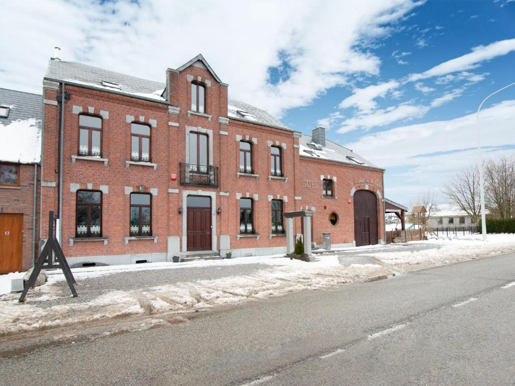 a red brick building on a snowy street at Beautiful Holiday Home in Cul des Sarts with Garden in Cul-des-Sarts