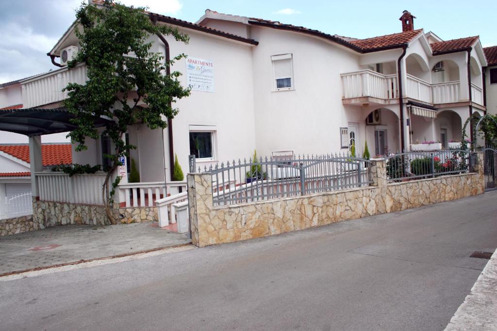 un edificio blanco con una valla y una calle en Apartments Gavric, en Trogir