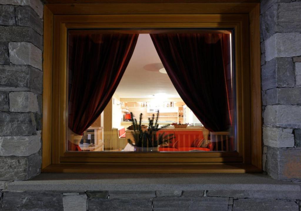 a window with red curtains in a room at Hotel de Gletscher in Gressoney-la-Trinité