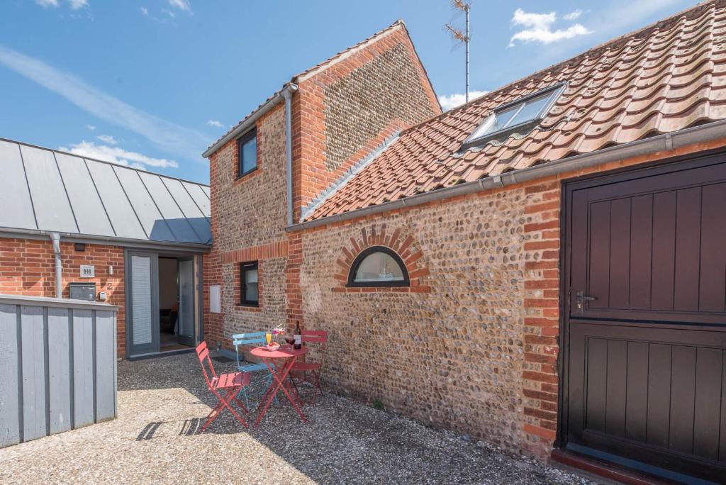 ein Backsteinhaus mit einem roten Tisch und zwei Stühlen in der Unterkunft Kipper Cottage, Southwold in Southwold