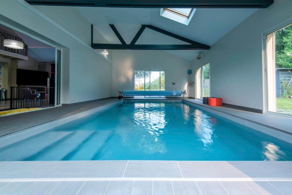 a swimming pool in a house with blue walls and windows at La Villa d'Elvine - Maison avec grand jardin in Verrie