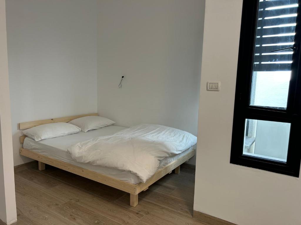 a bed with white sheets and pillows in a room at יחידת אירוח אור בזלת in Qiryat Shemona