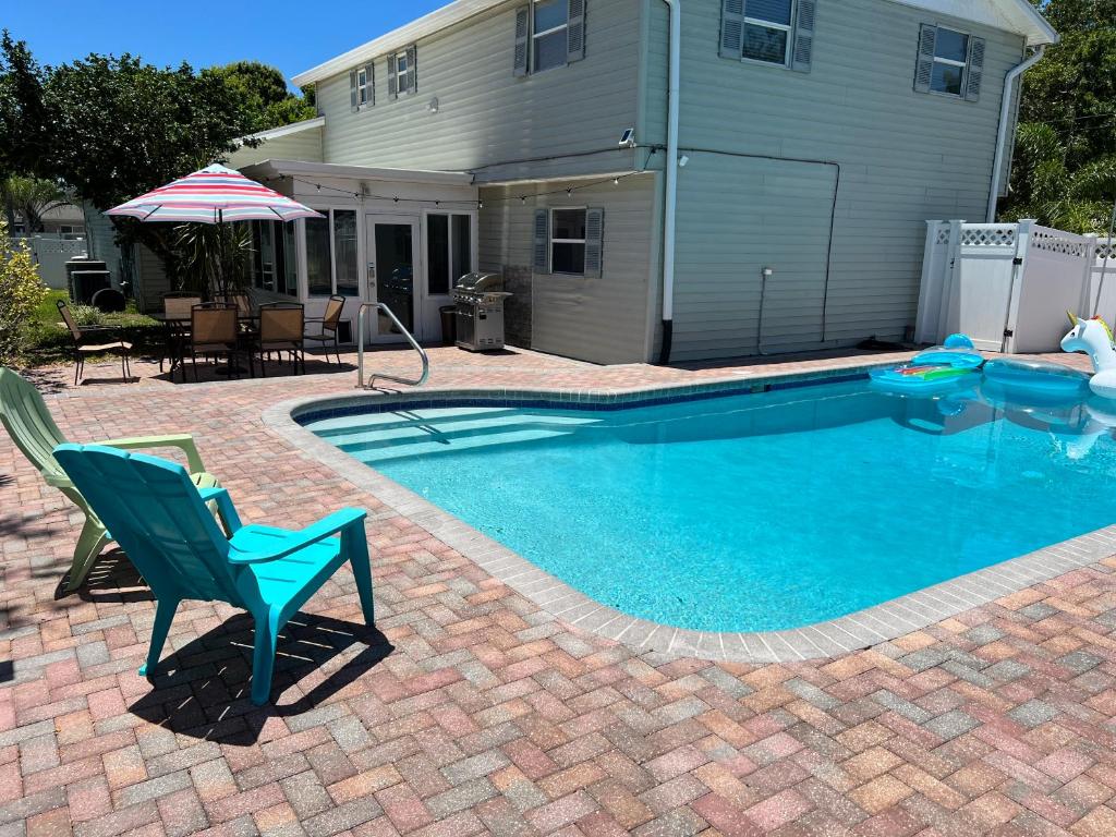 a swimming pool with a chair and a house at Poolside Paradise & Beach Bound in Seminole